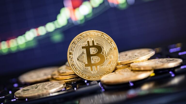 Moneta Bitcoin na monitorze z wykresem giełdowym